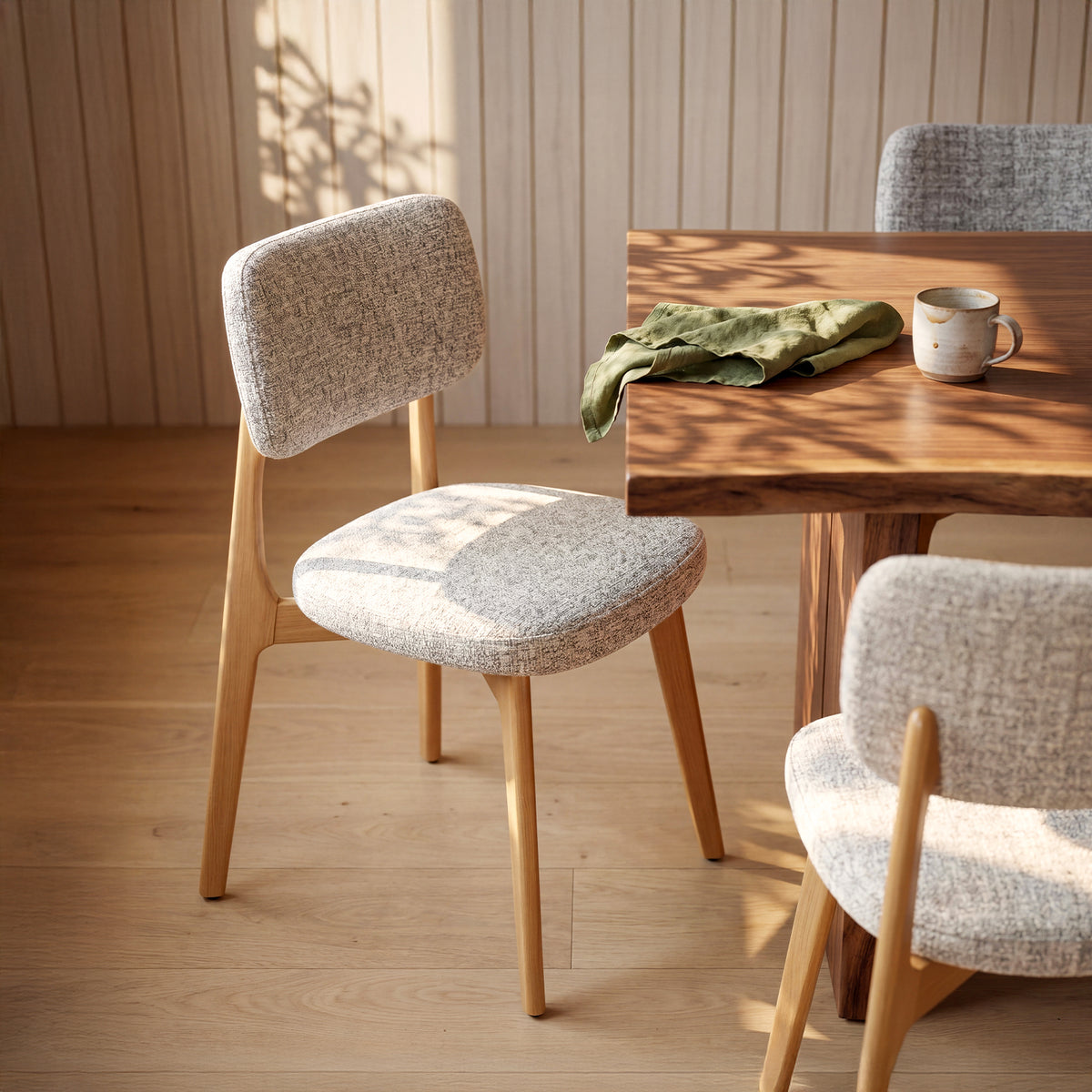 COLAMY NOYA Prime natural oak upholstered dining chair with textured mixed-weave fabric beside a wooden dining table